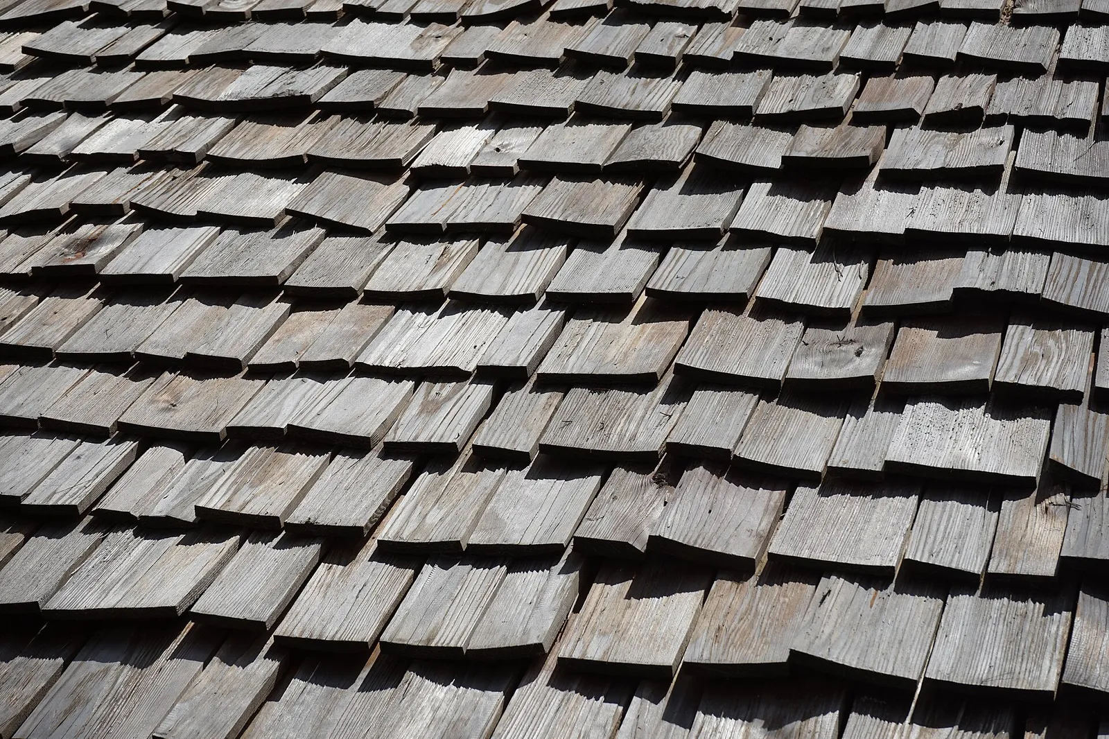 Toit de bardeaux gris, écailles décalées au vent